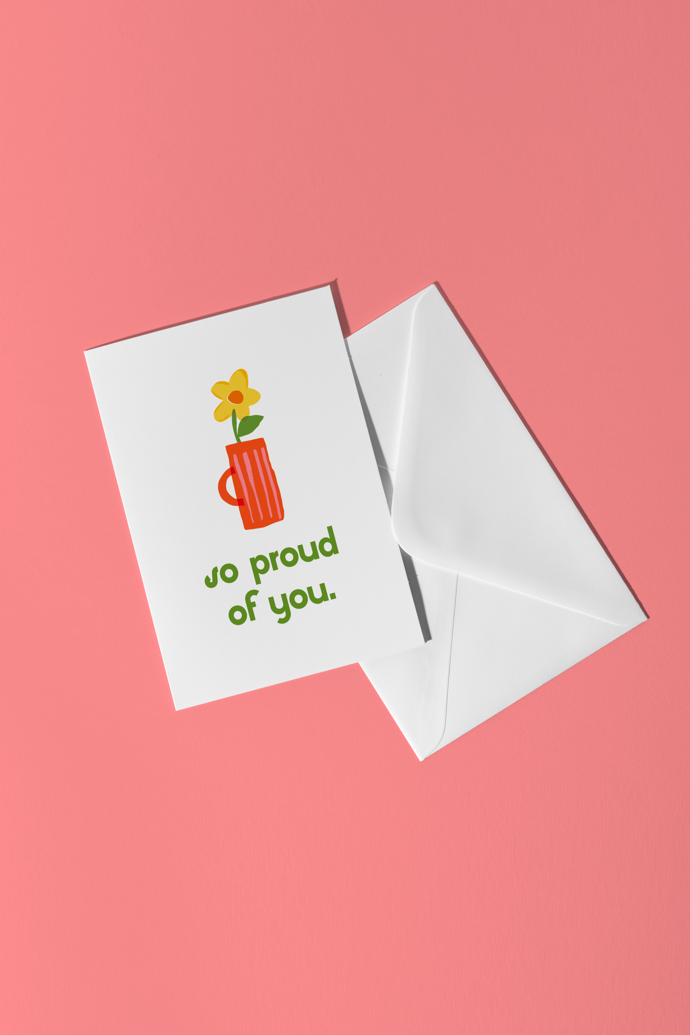 Greeting card with 'so proud of you' text and a cup with a flower on a pink background